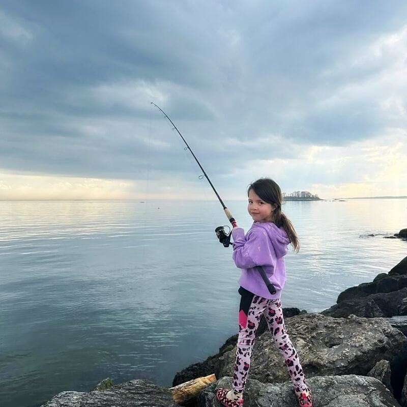 Young girls standing on rocks fishing.